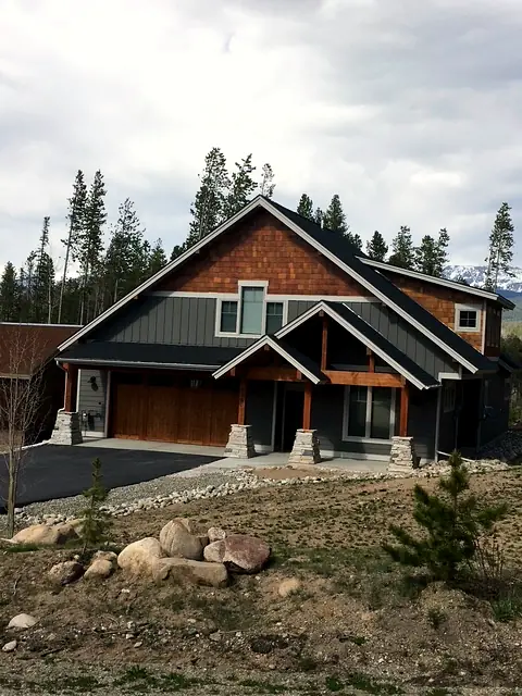Craftsman custom home with cedar shake gables, timber entry, and stone post bases