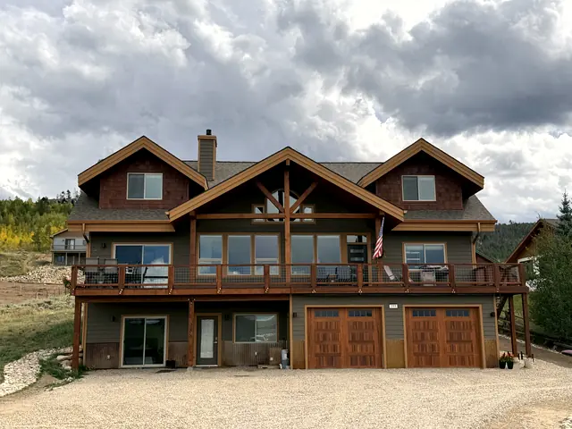 Finished timber-frame craftsman custom home in summer, with cedar garage doors, built by Rondeau Construction in Granby, Colorado