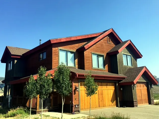 Red and cedar mountain duplex with wood garage doors and young aspens