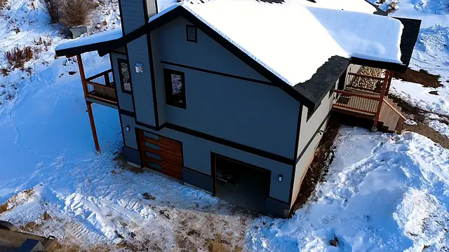 Aerial view of a finished custom home with attached deck in winter, Grand County, Colorado