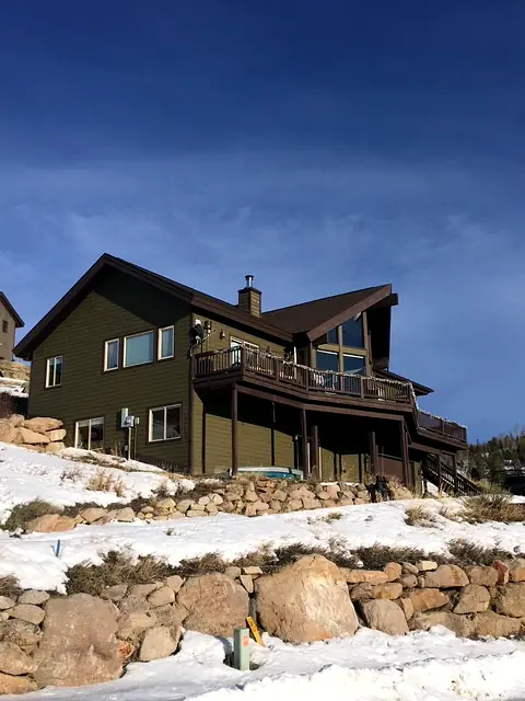 Two custom hillside homes built by Rondeau Construction on a rocky Grand County slope in winter