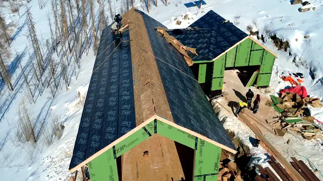 Roofing crew installing waterproof underlayment over fresh sheathing in Grand County